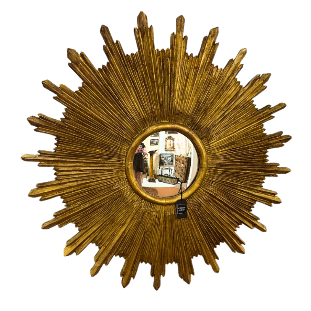 Gold sunburst mirror with a tag on a white background
