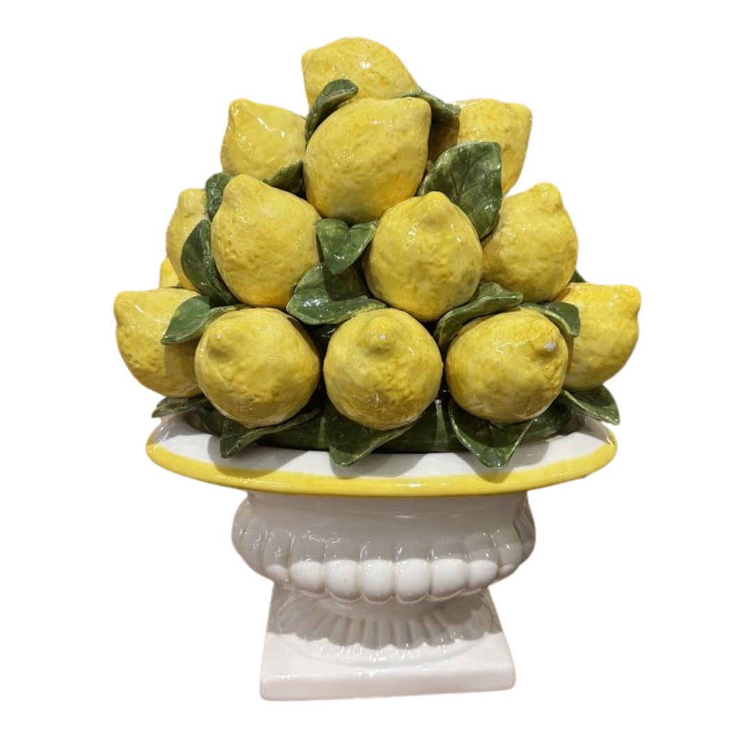 Decorative arrangement of lemons on a white pedestal with a white background