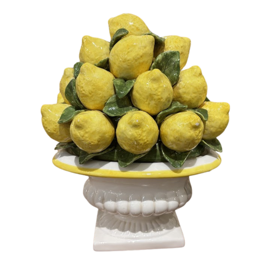 Decorative arrangement of lemons on a white pedestal with a white background