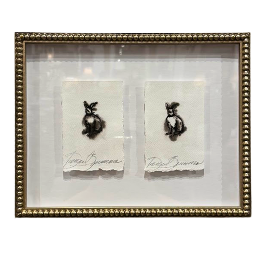 Two small artworks of rabbits in a gold frame on a white background