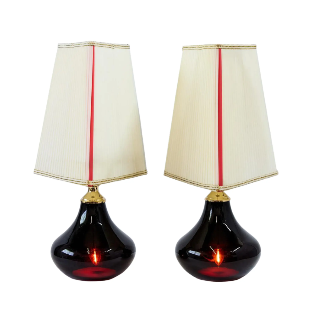 Two table lamps with black bases and white shades with red stripes on a white background