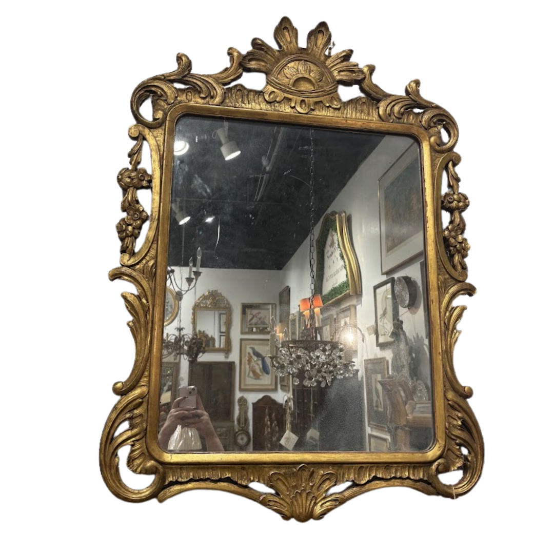 Decorative gold-framed mirror with intricate details on a white background