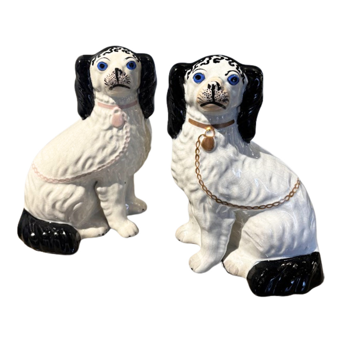 Two ceramic dog figurines with black and white markings on a white background