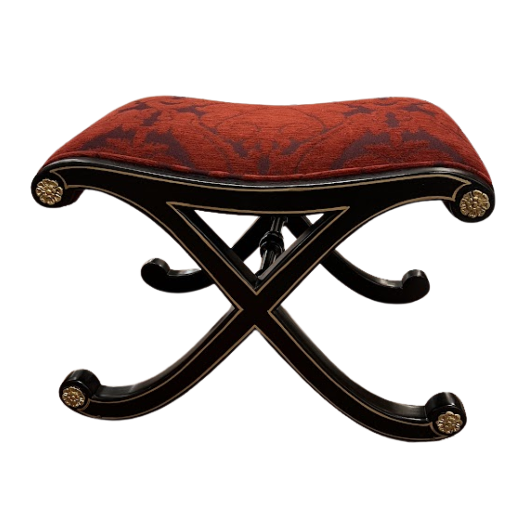 Decorative stool with red patterned cushion and black frame on a white background