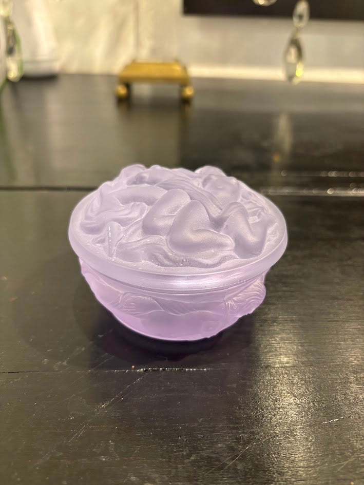 Purple translucent decorative box with intricate carvings on a black surface