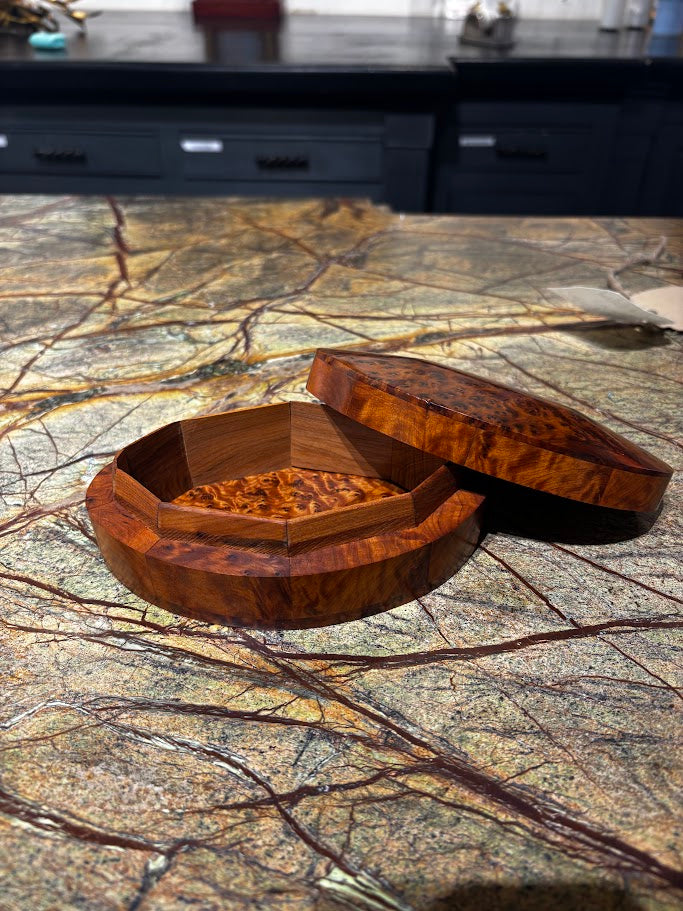 Wooden jewelry box with a lid open on a marble surface