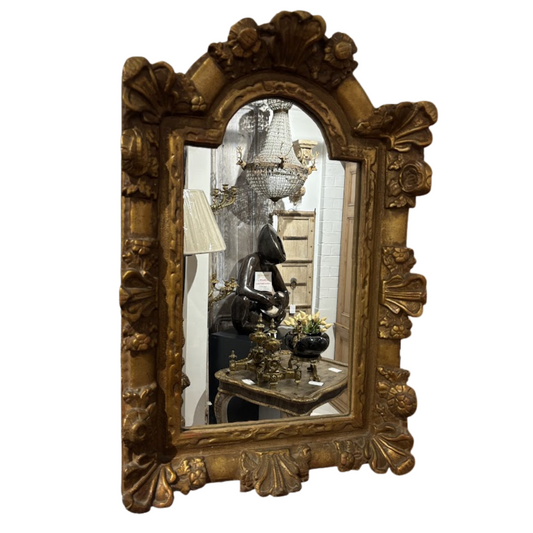 Decorative gold-framed mirror with intricate designs on a white background