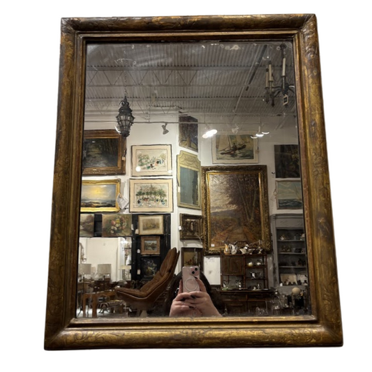 Vintage-style mirror with a gold frame reflecting an interior setting.