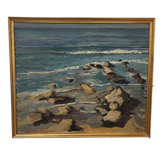 Painting of a coastal scene with rocks and ocean waves, framed in gold.