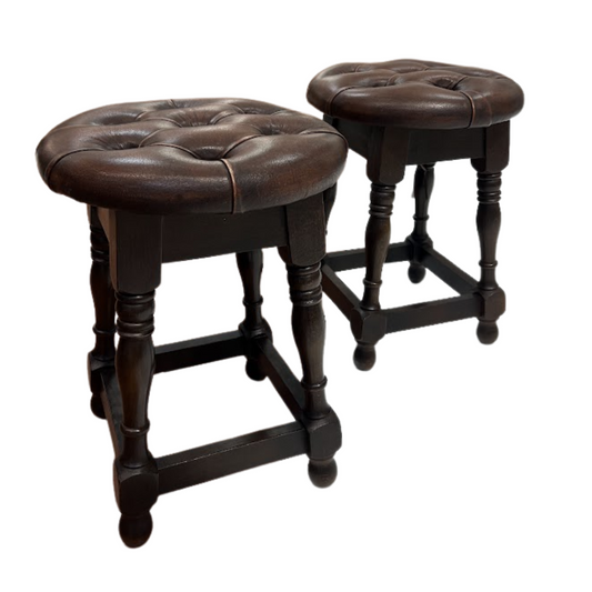 Two brown leather stools with wooden legs on a white background