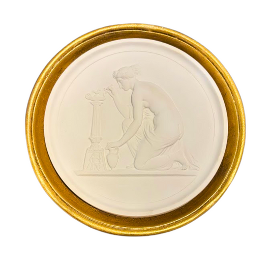 Round white object with embossed design on a gold rim against a white background