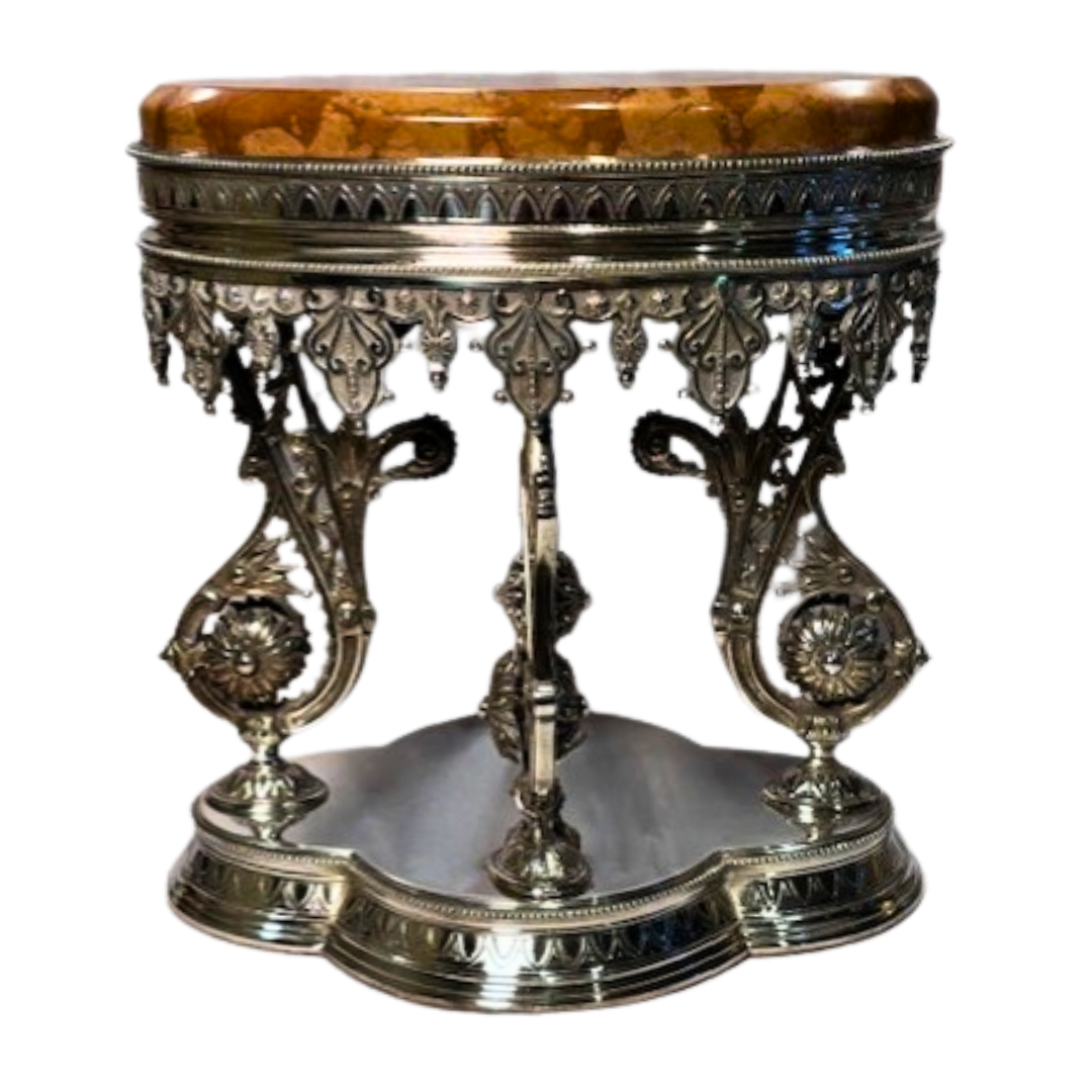 Decorative table with ornate silver base and amber-colored top on a white background