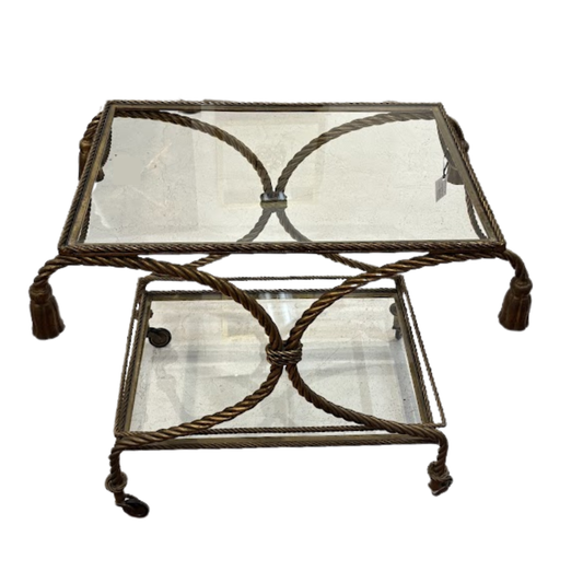 Two-tiered decorative table with glass top and metal frame on a white background