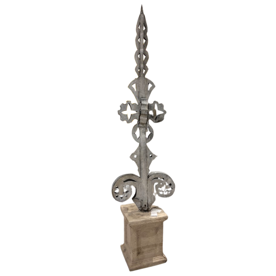 Decorative metal spire on a wooden base against a white background