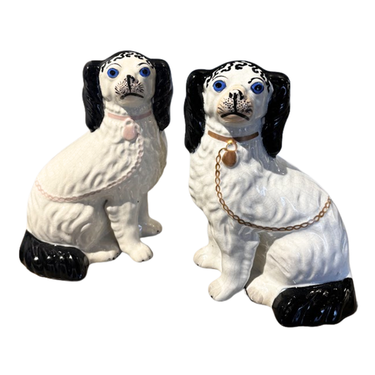Two ceramic dog figurines with black and white markings on a white background