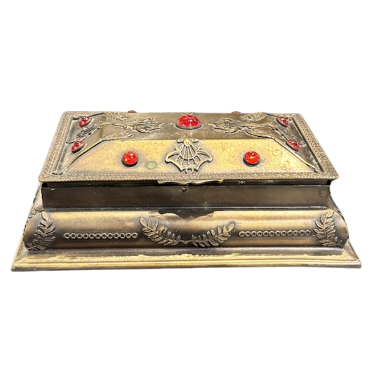 Decorative metallic box with red gemstones on a white background