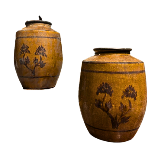 Two brown ceramic jars with floral designs on a white background
