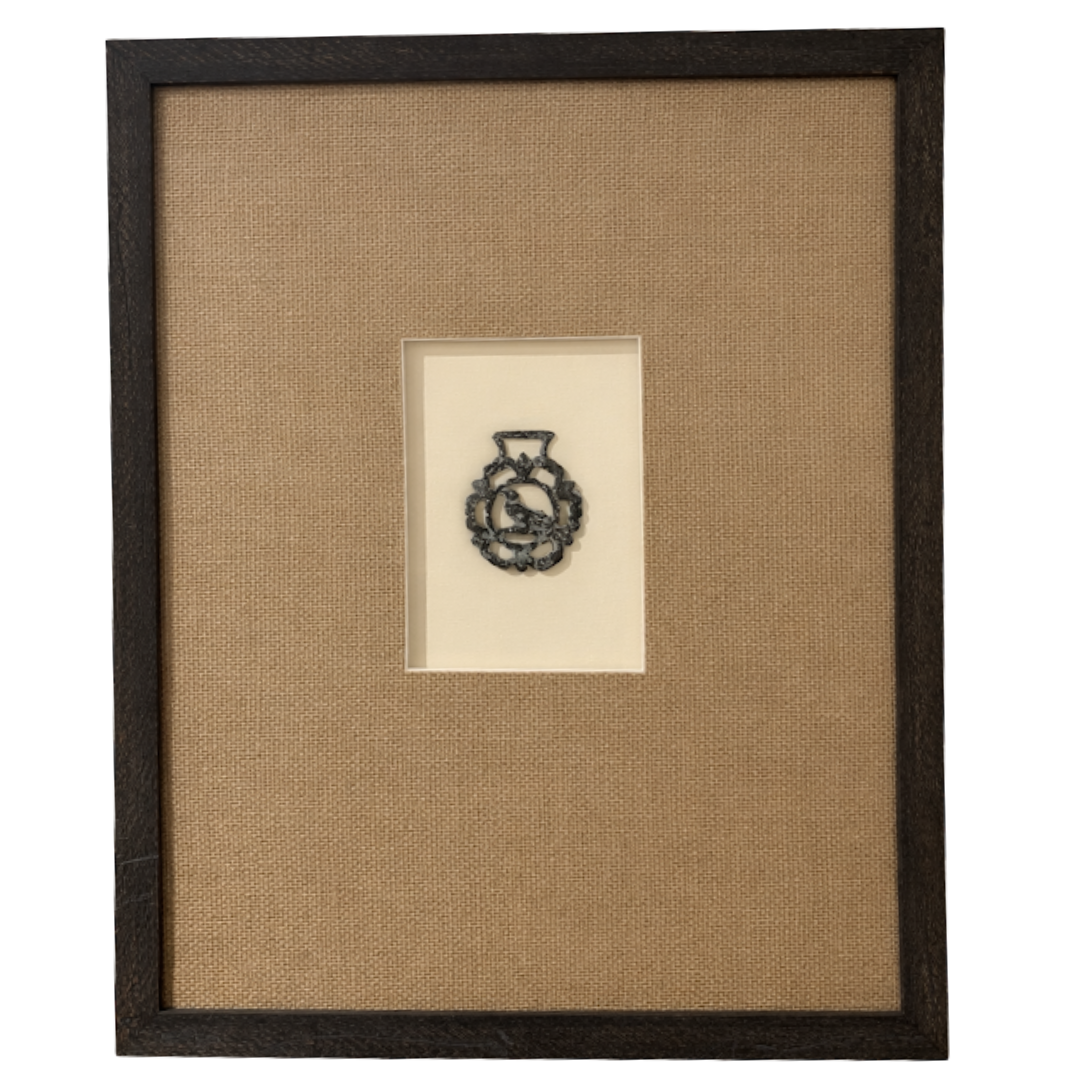 Framed artwork with a small embroidered design on beige fabric