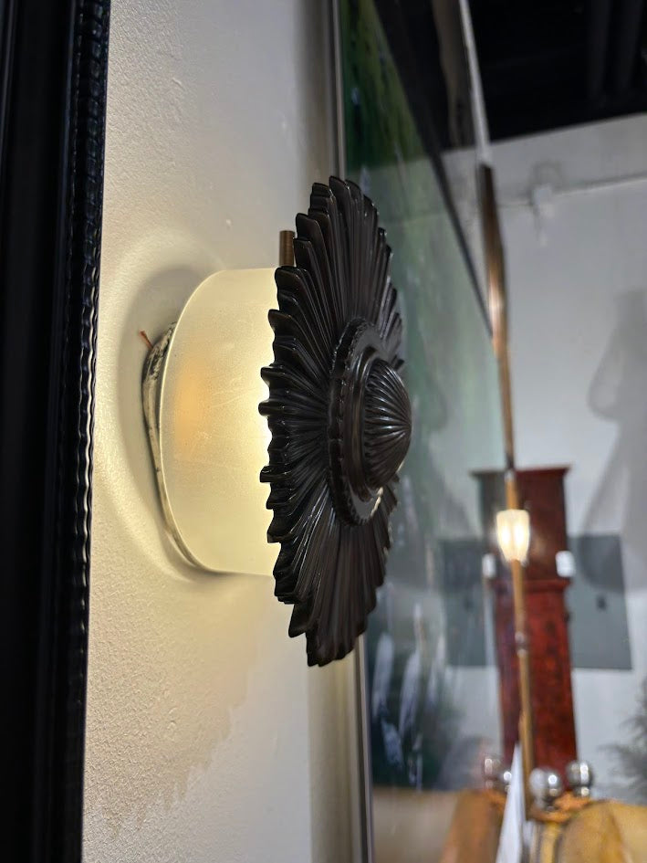 Decorative wall sconce with a black floral design on a white wall.